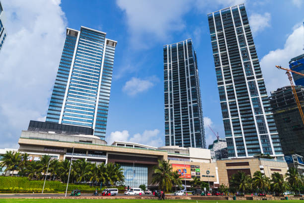 Colombo, Sri Lanka - December 3, 2021: Colombo downtown street view with skyscrapers under blue cloudy sky, ordinary people and cars are on the street